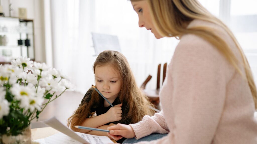 Mother doing homework at home with her little daughter